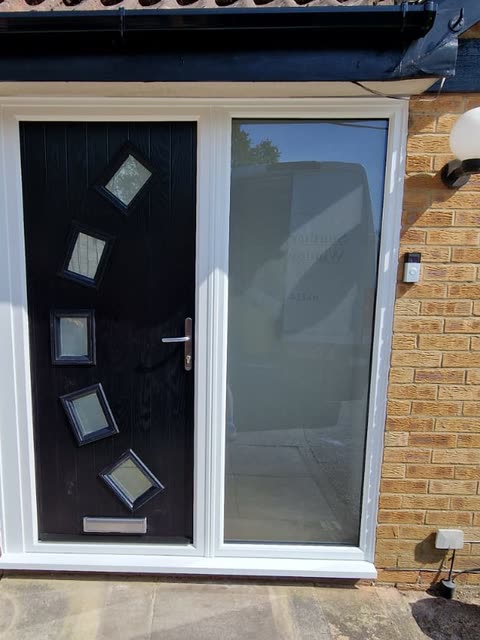 Black contemporary front door with angled square glass panels and a full-height side light