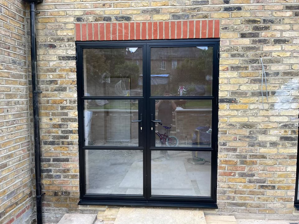 Black French doors with slim glazing bars in a new brick opening