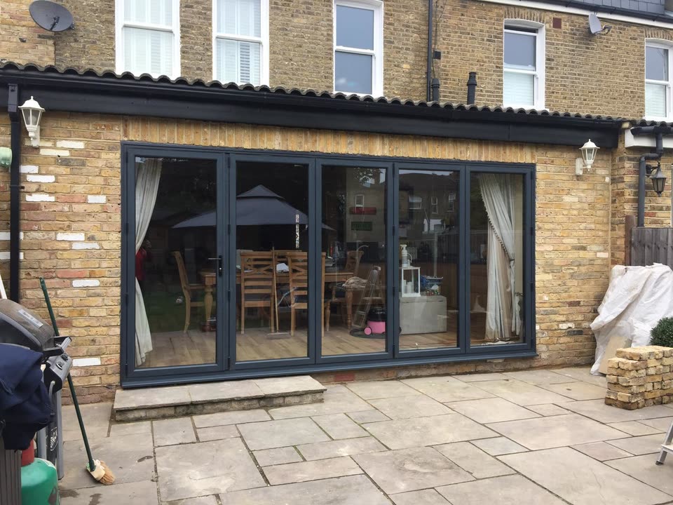 Grey bi-fold doors across the back of a rear extension
