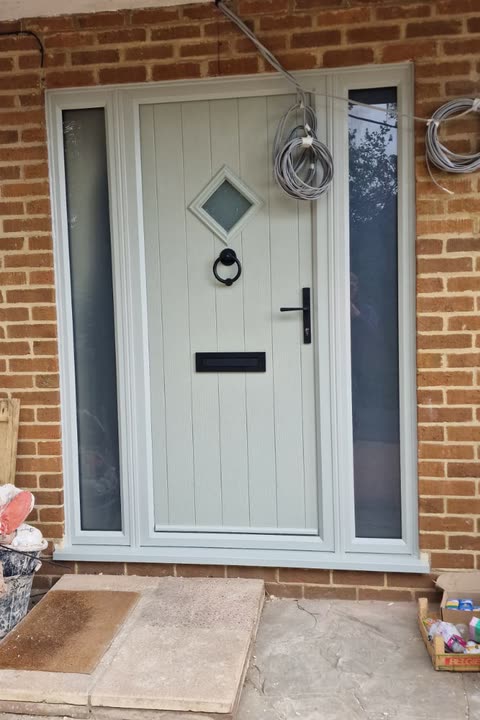 Light grey front door with a diamond glass panel and glazed side lights