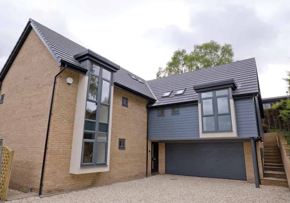 Modern house with tall grey windows and a grey garage door
