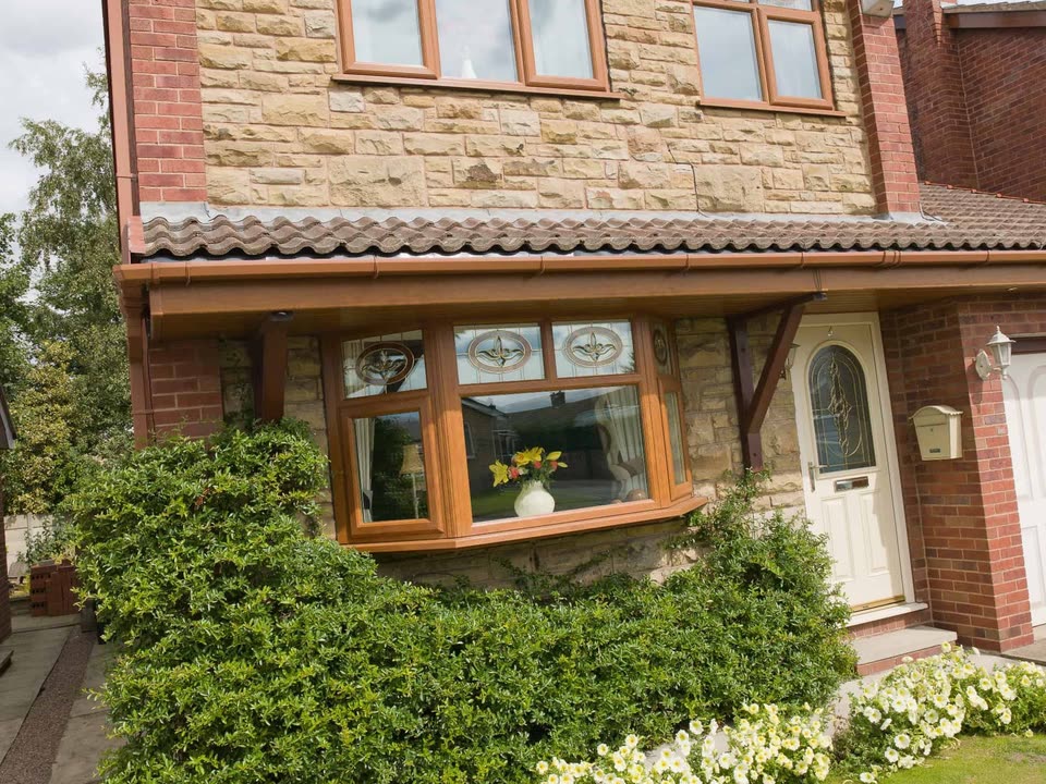 Stone and brick house with oak effect bay windows and a front garden