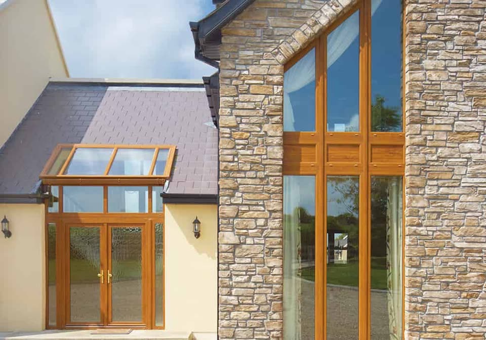 Golden oak effect uPVC porch and tall windows on a stone house
