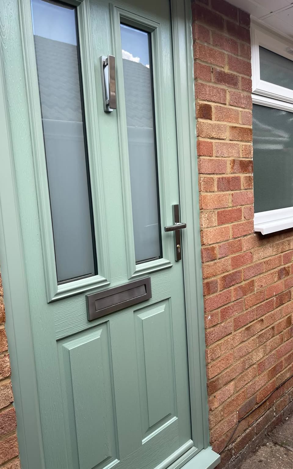 Sage green front door with tall glazed panels