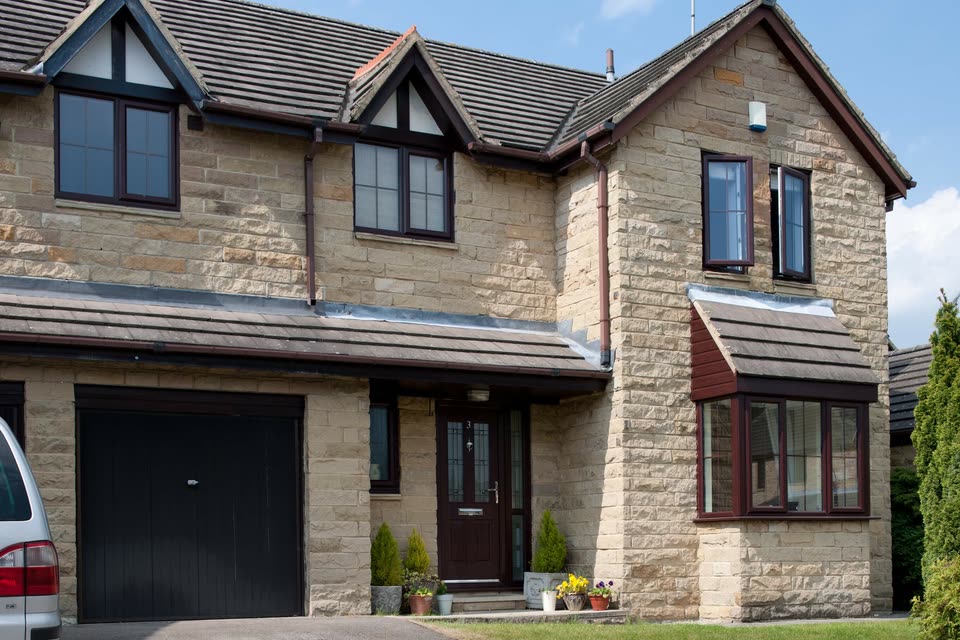 Stone house with dark grey windows and a matching front door