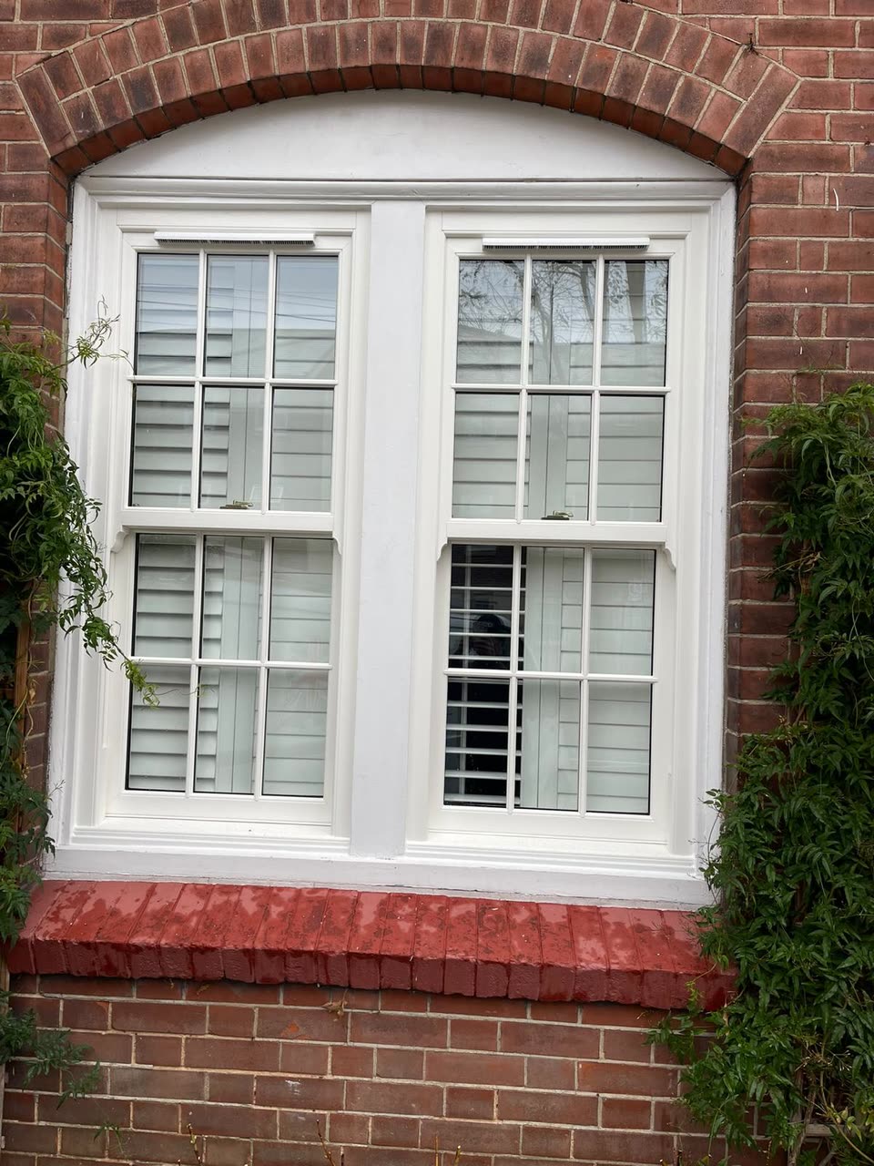 White sliding sash window with Georgian bars under an arched brick head