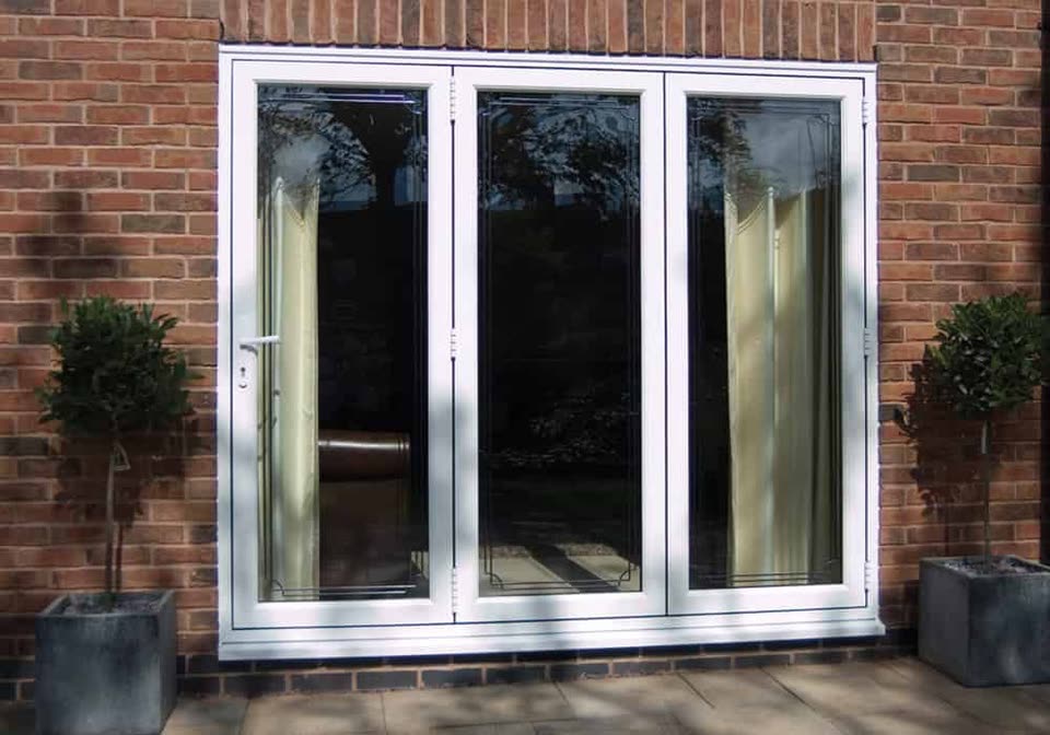 White uPVC French doors with side panels in a brick wall